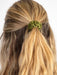 Green hair tie holding a ponytail with blonde hair on a white background