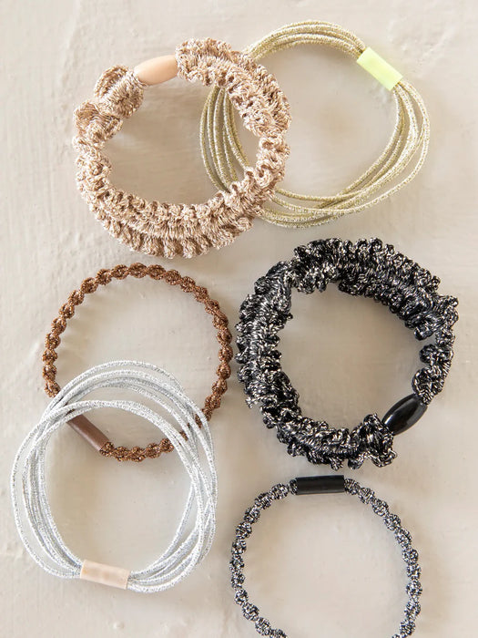 Set of six hair ties in various colors on a textured surface