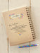 Notebook with a message about kindness on a wooden surface, accompanied by a colorful pen.