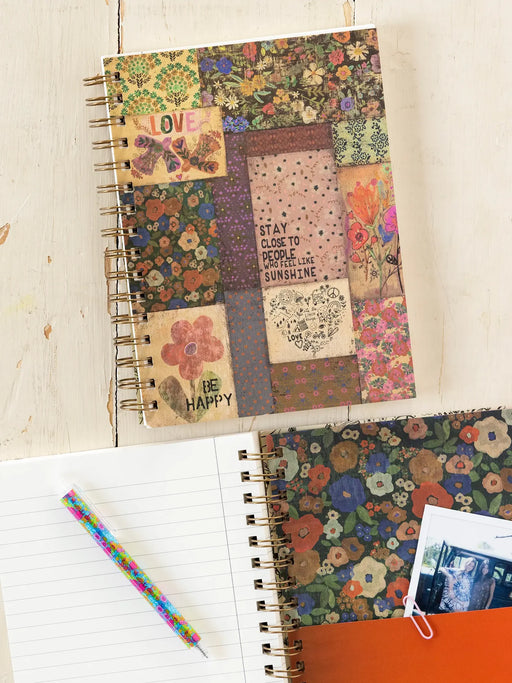 Notebook with colorful floral and text pattern on a wooden surface