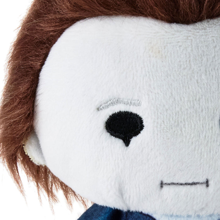 Close-up of a plush doll's face with white fabric, brown hair, a black embroidered eye, and a blue neck area on a white background.