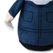 Close-up of a plush toy wearing blue denim-style overalls with black stitched details, a white collar, and a black base, shown against a white background.