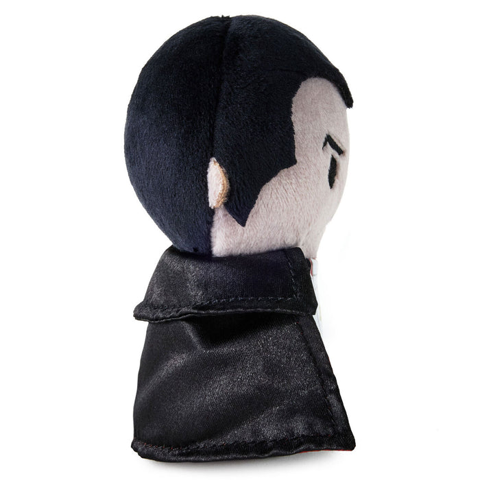 A plush doll head with black hair, a pale gray face, and a black cape, shown from a side-back angle on a white background.