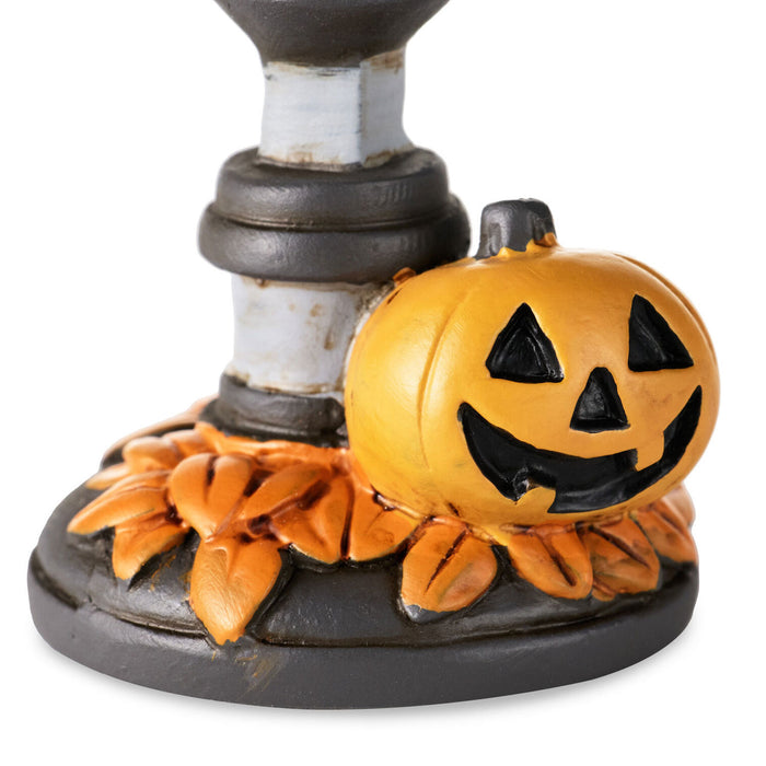 A Halloween-themed decorative base featuring a carved orange jack-o'-lantern pumpkin next to a dark gray and white candlestick, with faux orange leaves around the bottom, shown on a white background.
