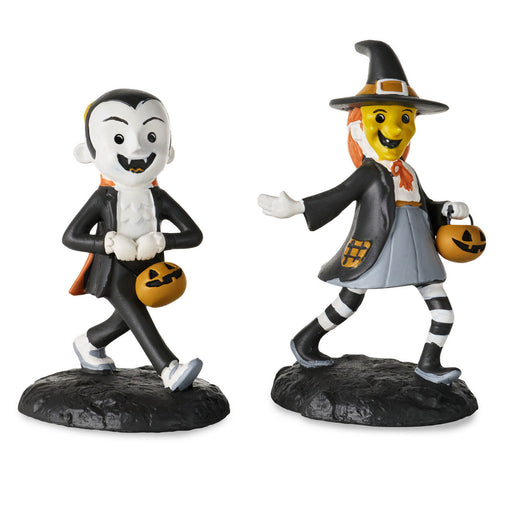Two Halloween figurines on a plain white background: a vampire figure in a black suit with white hair and a pumpkin bucket, and a witch figure in a black hat and gray skirt with orange accents and a pumpkin bucket.