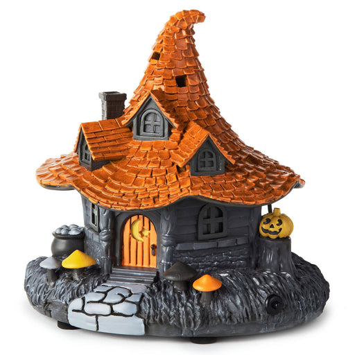 A decorative haunted house Halloween ornament with a pointed orange roof, dark gray body, orange door, jack-o'-lanterns, cauldron, and mushrooms on a white background.