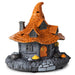 A decorative miniature haunted house figurine with a pointed orange roof, gray stone walls, an orange door with a crescent moon, cauldrons, mushrooms, and a stone path on a white background.