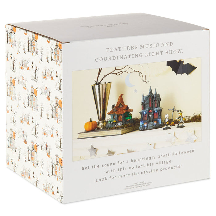 A white retail box for a collectible Halloween light show, featuring printed artwork of haunted houses, bats, pumpkins, and decorative props on the front panel, with text describing music and coordinating light show features.