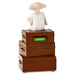 A collectible figurine of Dory from Finding Nemo sitting on top of three stacked brown storage boxes. The middle box features a green label with the word 'AUGUST' in white.