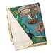 A folded throw blanket featuring a Hogwarts Castle illustration from Harry Potter, with a green and teal castle scene, a boat, and a cream-colored reverse side.