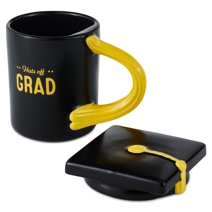 Black mug with yellow handle and 'Hats off GRAD' text, accompanied by a graduation cap-shaped coaster.