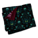 A folded plush blanket with a black background, teal gothic damask patterns, and green owl faces, showing a burgundy sherpa lining on one side.
