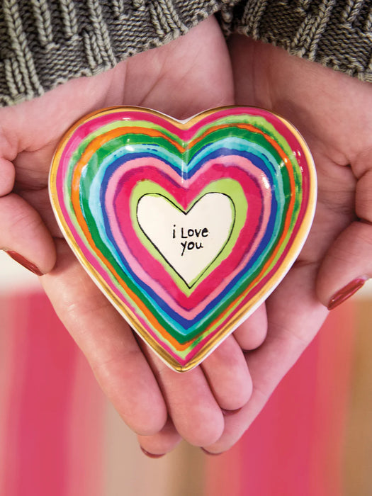 Heart-shaped object with 'i love you' text held in hands against a blurred background