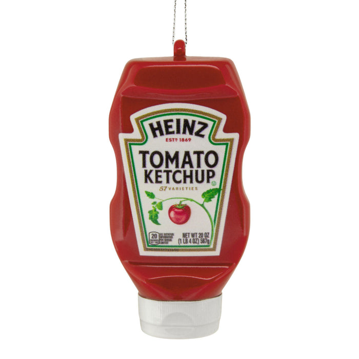 A red Heinz Tomato Ketchup squeeze bottle ornament or decoration with a white cap and a hanging loop at the top, shown on a plain white background.