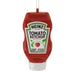 A red Heinz Tomato Ketchup squeeze bottle ornament or decoration with a white cap and a hanging loop at the top, shown on a plain white background.