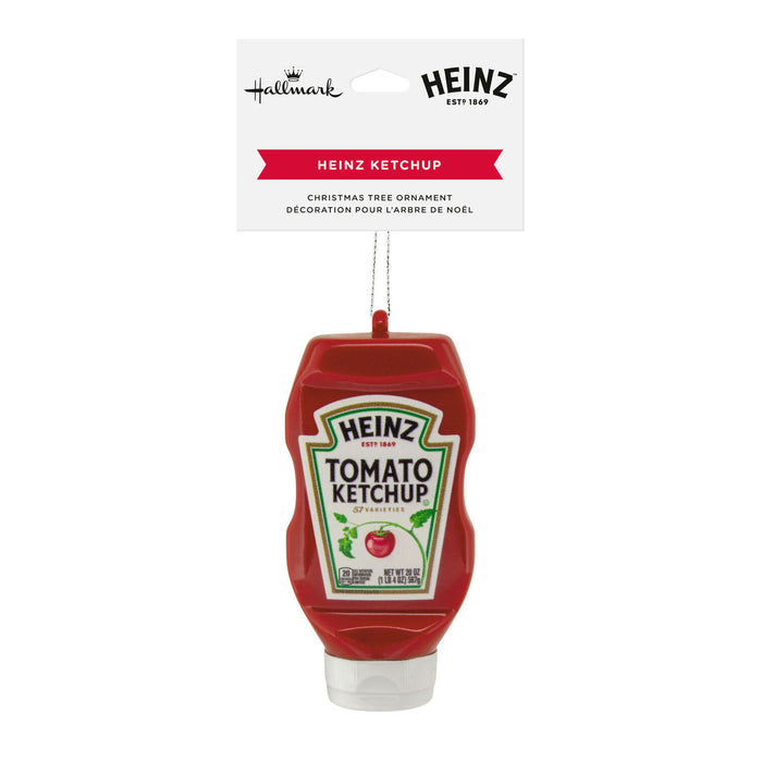 Heinz Ketchup Christmas tree ornament hanging from a white retail card. The ornament is shaped like a red Heinz ketchup bottle with the Heinz logo and Tomato Ketchup label visible, on a plain white background.