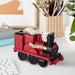 Red train-shaped tape dispenser on a desk with stationery items in the background