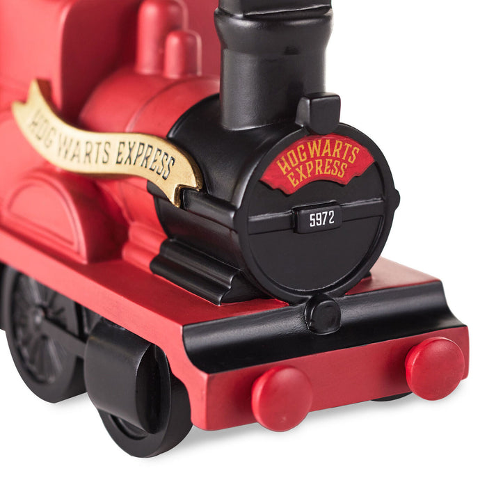 Close-up of a red toy train engine with 'Hogwarts Express' branding on a white background