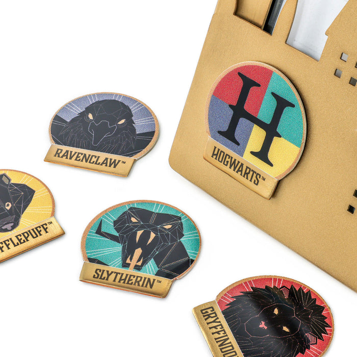 Set of Harry Potter house badges with a brown envelope in the background