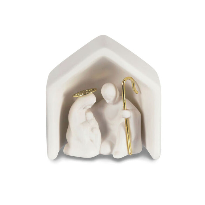 White nativity scene figurine with gold accents inside a hexagonal stable on a white background