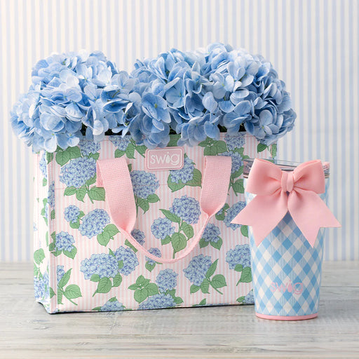 Floral-patterned bag with pink ribbon and a small container with a pink bow on a striped background