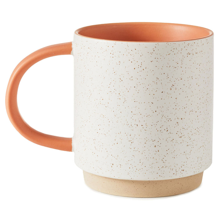 Speckled ceramic mug with terracotta handle and rim on a white background
