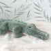 Plush alligator toy on a soft surface with a light background