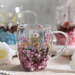 Clear mug with floral design filled with pink flowers on a table with blurred background