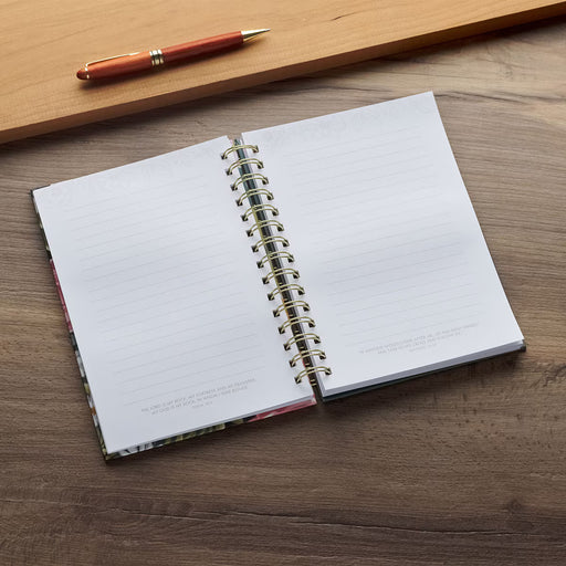 Open notebook with spiral binding on a wooden surface, accompanied by a pen.