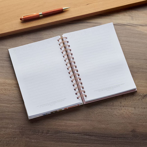 Open notebook with spiral binding on a wooden surface, accompanied by a pen.