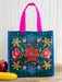 Colorful floral-patterned tote bag with pink handles on a wooden surface.