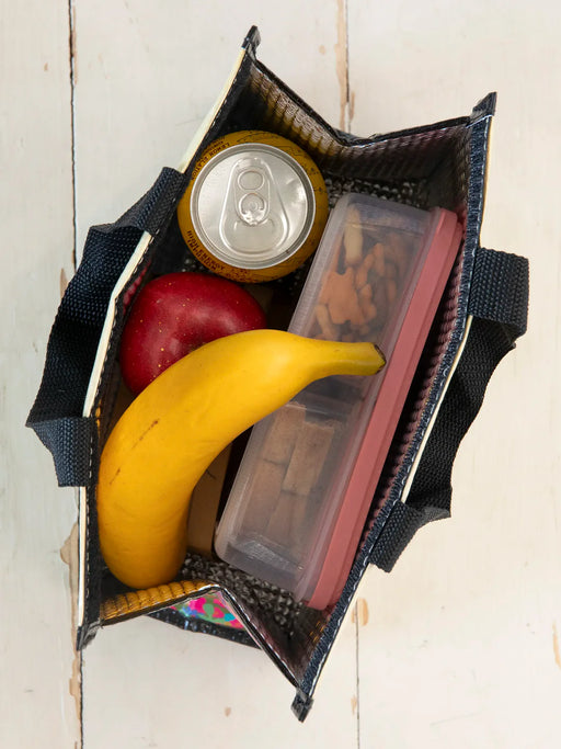 Reusable shopping bag with a banana, apple, and snack container on a wooden surface