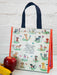 Reusable shopping bag with dog illustrations and text, next to an apple and banana on a white surface.