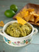 Guacamole in a decorative bowl with a tortilla chip on a wooden surface