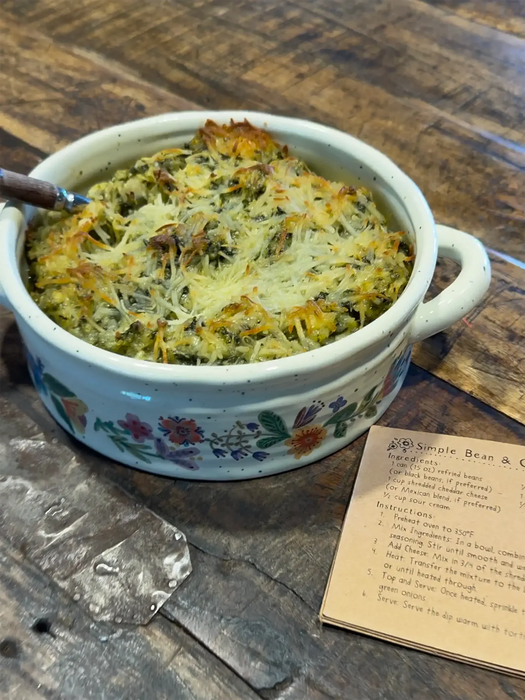 Casserole dish with baked dish on a wooden table with a recipe card.
