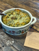 Casserole dish with baked dish on a wooden table with a recipe card.