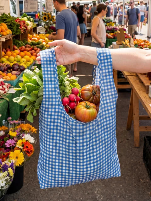 Blue checkered bag filled with fresh produce held in front of a market scene.