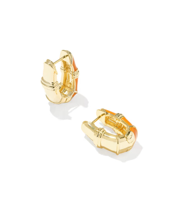A pair of gold huggie hoop earrings with a textured, geometric bamboo-inspired design and a small orange accent, shown on a clean white background.