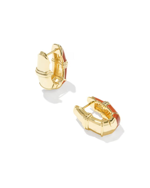 A pair of gold huggie hoop earrings with a textured, segmented design and a glossy terracotta red enamel accent, shown on a clean white background.