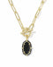 A gold paperclip chain necklace with a toggle clasp and a small oval black onyx pendant, shown on a plain white background.