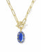 A gold paperclip chain necklace with a toggle clasp and a dangling blue oval gemstone pendant, shown on a clean white background.
