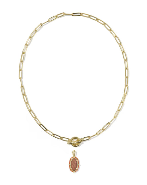 A gold paperclip chain necklace with a toggle clasp and a small oval pendant featuring a pinkish-orange stone, shown on a plain white background.