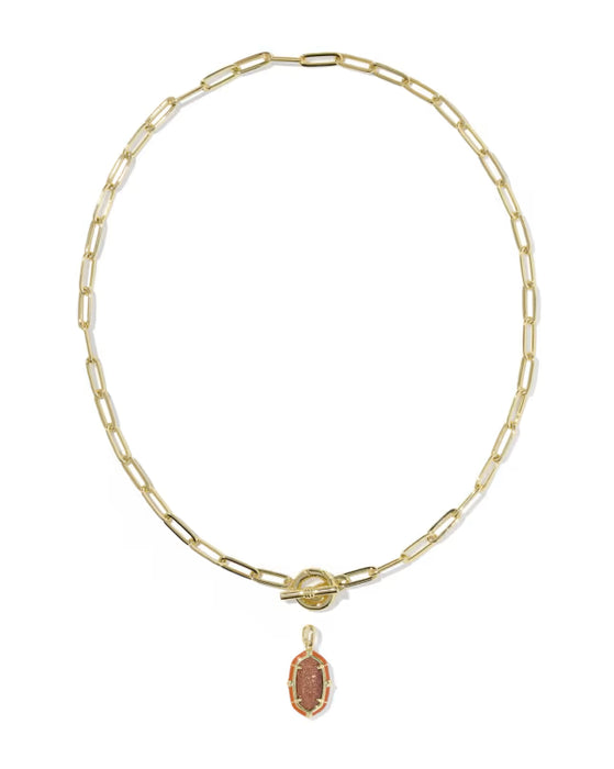 A gold paperclip chain necklace with a toggle clasp and a small oval pendant featuring a pinkish-orange stone, shown on a plain white background.