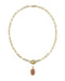 A gold paperclip chain necklace with a toggle clasp and a small oval pendant featuring a pinkish-orange stone, shown on a plain white background.