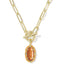 A gold paperclip chain necklace with a toggle clasp and a dangling oval orange gemstone pendant, shown on a clean white background.