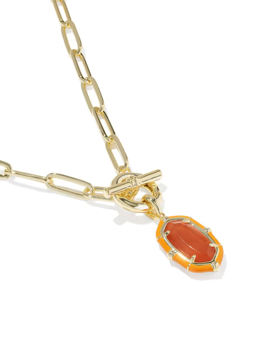 A gold chain necklace featuring a toggle clasp and a dangling oval pendant with a bright orange inlay and a central clear gemstone, shown on a white background.