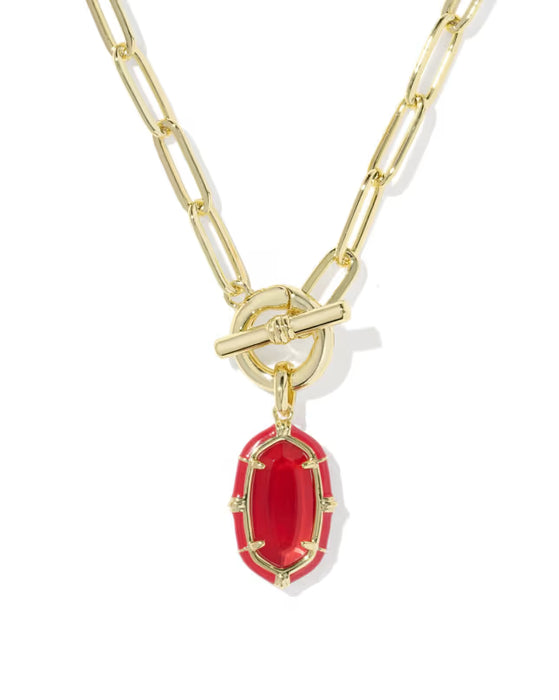 A gold paperclip chain necklace with a toggle clasp and a red oval pendant, shown on a clean white background.