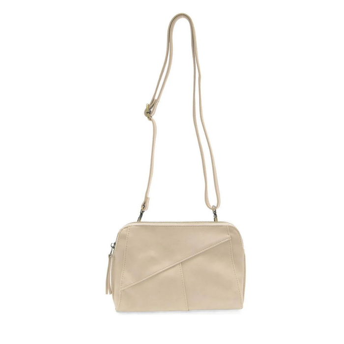 A light beige faux-leather shoulder bag with a diagonal front flap detail, a matching tassel zipper pull, and a thin adjustable shoulder strap, shown against a plain white background.