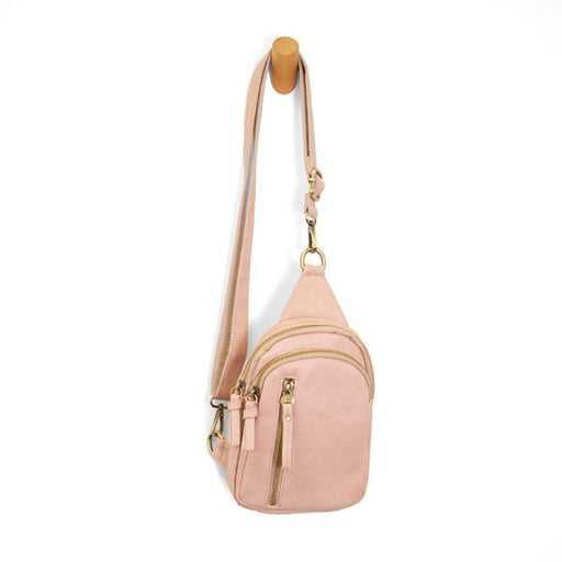 Pink crossbody bag with gold zippers on a white background
