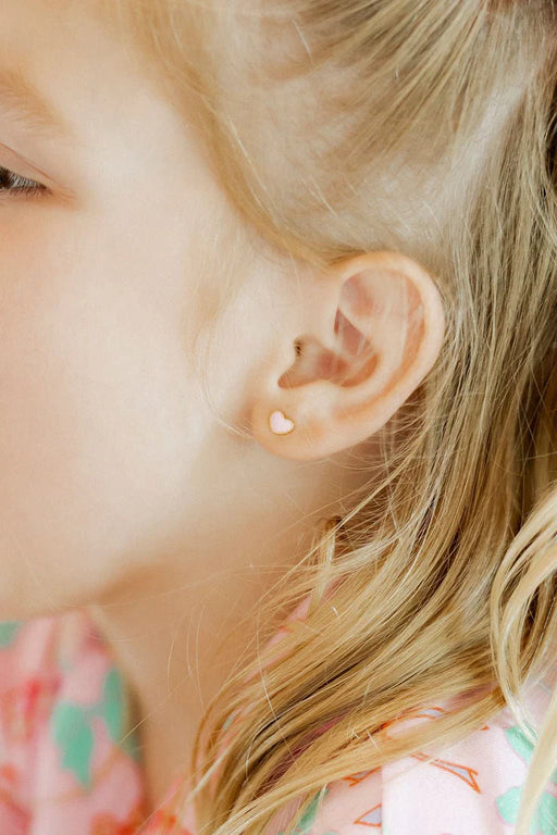 Close-up of a young girl's ear with blonde hair and a floral patterned garment.